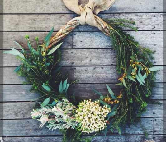 Green wreath with white flowers on a wooden surface
